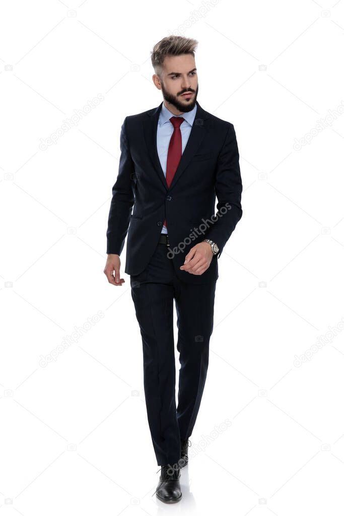 sexy young businessman looking to side and walking isolated on white background