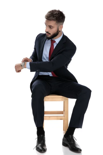 Νεαρός Επιχειρηματίας Κοστούμι Δείχνει Ρολόι Στο Ρολόι Κάθεται Απομονωμένος Λευκό — Φωτογραφία Αρχείου