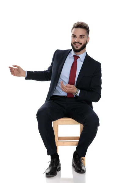 Glücklicher Junger Geschäftsmann Lächelt Und Präsentiert Zur Seite Sitzt Isoliert — Stockfoto