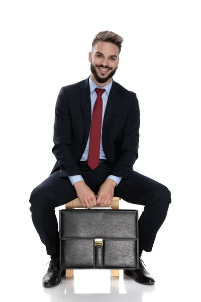 Szczęśliwy Młody Biznesmen Uśmiecha Się Trzyma Walizkę Siedzi Odizolowany Białym — Zdjęcie stockowe