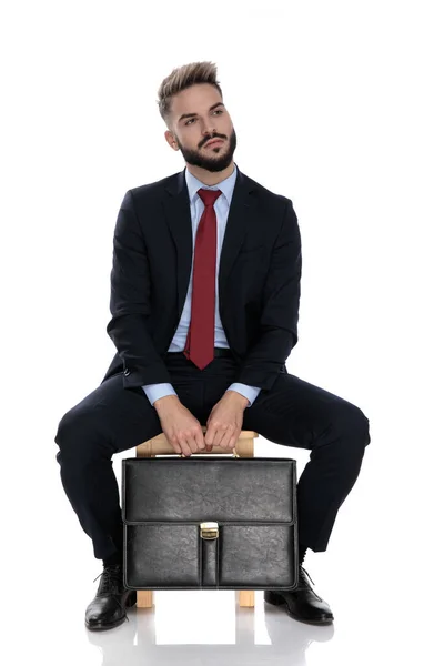 Pensativo Joven Empresario Sosteniendo Maleta Pensando Sentado Aislado Sobre Fondo — Foto de Stock