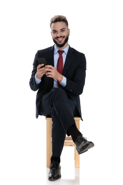 Feliz Jovem Empresário Sorrindo Segurando Telefone Sentado Isolado Fundo Branco — Fotografia de Stock