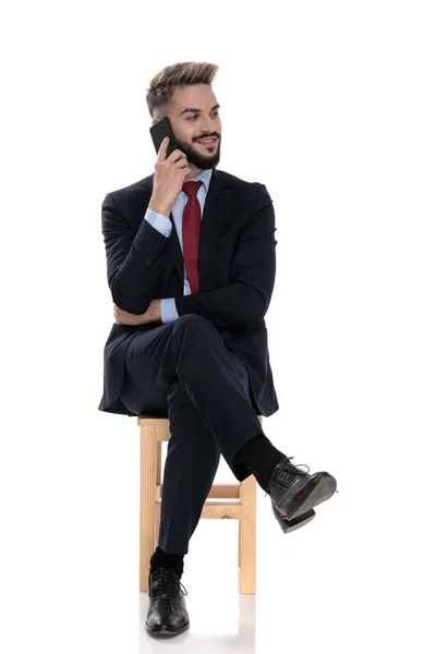 Jovem Feliz Falando Telefone Olhando Para Lado Sentado Isolado Fundo — Fotografia de Stock
