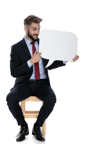 Junger Geschäftsmann Schaut Und Präsentiert Sprechblase Zur Seite Sitzt Isoliert — Stockfoto