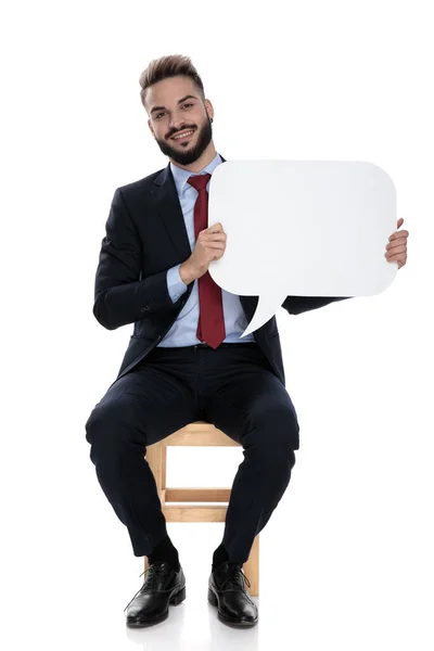 Feliz Joven Empresario Sonriendo Presentando Burbuja Del Habla Sentado Aislado — Foto de Stock