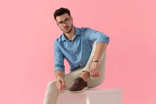 Atrakcyjny Biznesmen Noszący Okulary Siedzący Nogą Spoczywającą Kostce Patrzący Kamerę — Zdjęcie stockowe