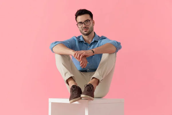 Молодой Бизнесмен Очках Сидящий Ножками Кубе Смотрящий Камеру Счастливый Розовом — стоковое фото