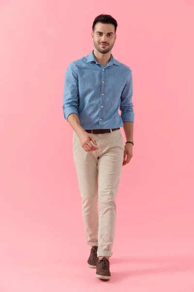 青いシャツを着たセクシーなビジネスマンが歩きカメラを見て幸せなピンクのスタジオの背景 — ストック写真