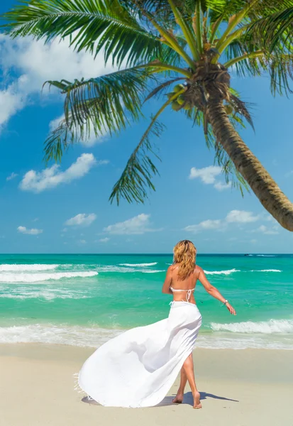 Mladá žena chůze na idylické pláži — Stock fotografie