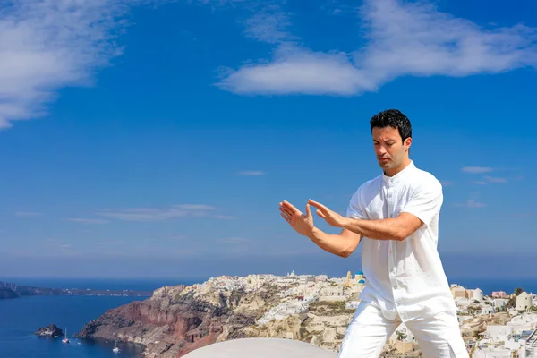 Bonito homem praticando Tai Chi dos telhados em Oia Santorini — Fotografia de Stock