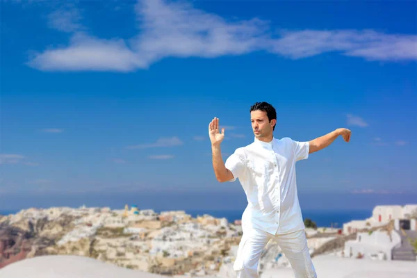 Schöner mann praktiziert tai chi von den dächern in oia santorini — Stockfoto