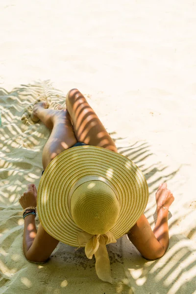 Женщина на пляже под пальмой с листовой тенью — стоковое фото