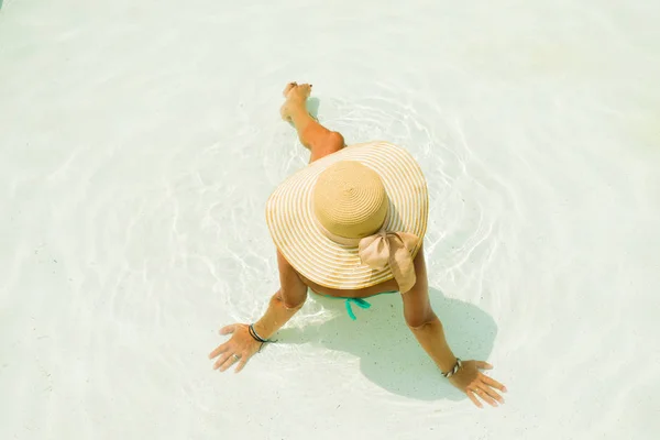 Ung kvinna sitter på kanten av poolen. — Stockfoto