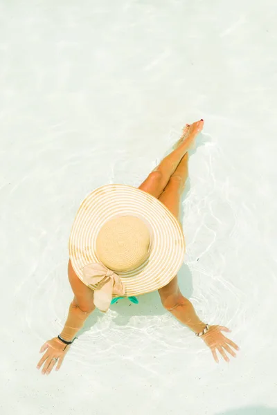Ung kvinna sitter på kanten av poolen. — Stockfoto
