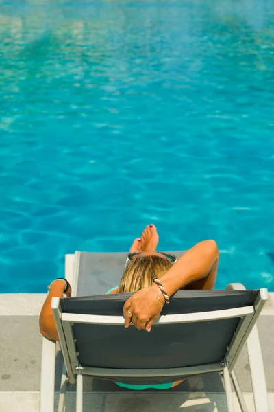 Mulher desfrutando na espreguiçadeira na piscina — Fotografia de Stock