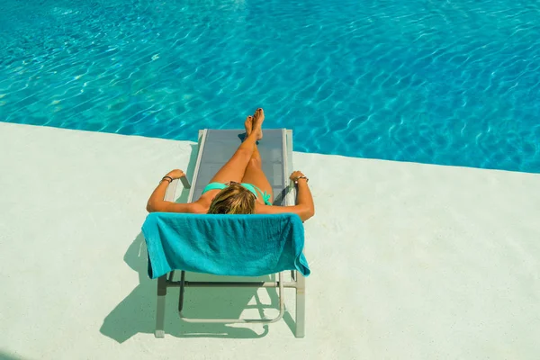 Kvinna njuter på solsäng vid poolen — Stockfoto