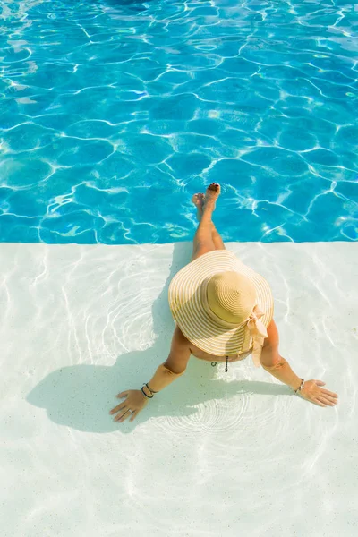 Jovem mulher sentada na borda da piscina. — Fotografia de Stock