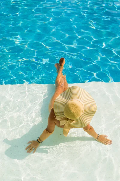 Ung kvinna sitter på kanten av poolen. — Stockfoto