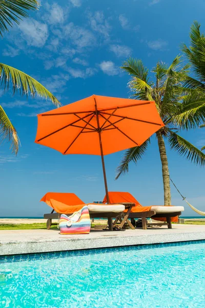 Deckchairs in tropical resort hotel pool — Stock Photo, Image