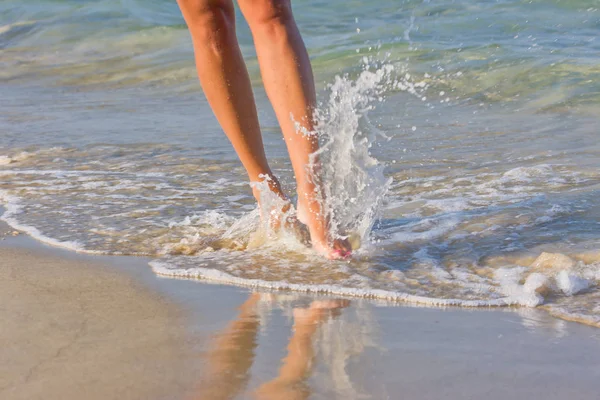 Die Beine der Frau gehen am Sand am Meer entlang. — Stockfoto