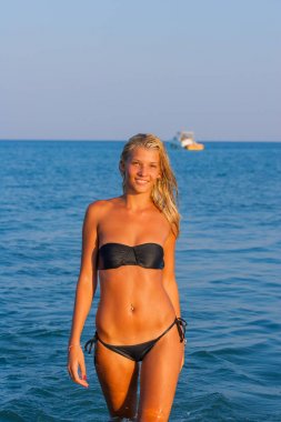 Gece karanlığında bir sığ denizde yürüyen bir bikini bir kadın