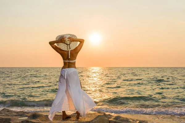 Vrouw hoed op het strand bij zonsondergang — Stockfoto