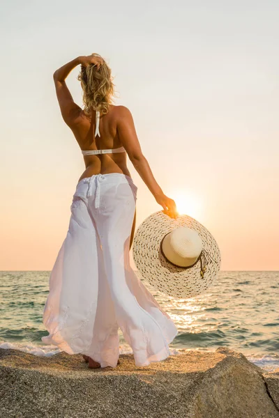 Vrouw hoed op het strand bij zonsondergang — Stockfoto