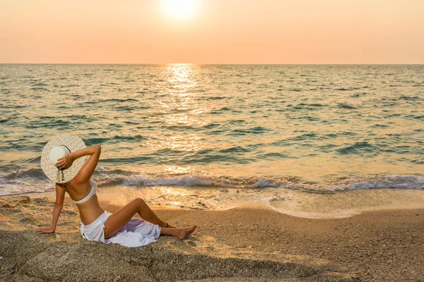 Vrouw hoed op het strand bij zonsondergang — Stockfoto