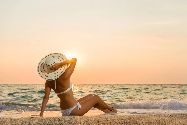 Vrouw in bikini en stro hoed op het strand — Stockfoto
