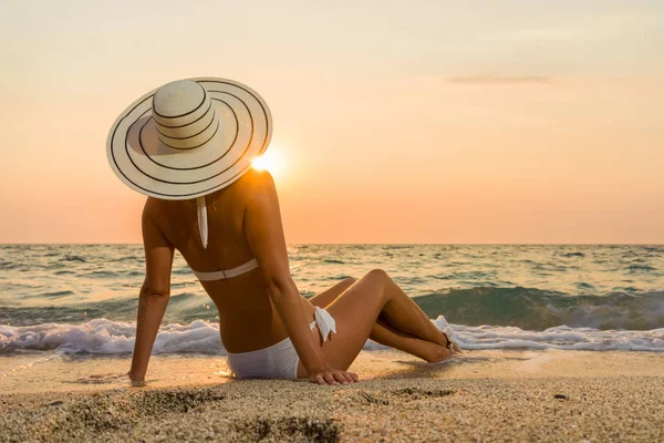 Vrouw in bikini en stro hoed op het strand — Stockfoto
