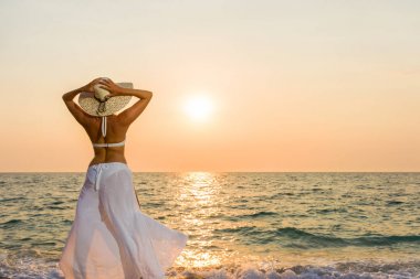 Kadın şapka gün batımında sahilde