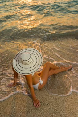 Plajda bikini ve saman şapkalı kadın