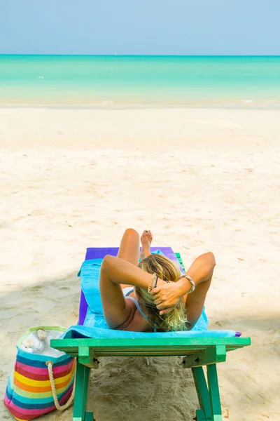 Kvinna sitter på en stol på stranden — Stockfoto