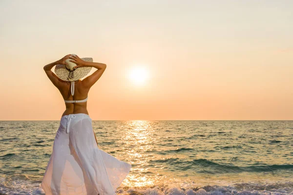 Kadın şapka gün batımında sahilde