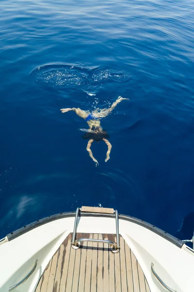 Ung kvinna simning av segelbåten — Stockfoto
