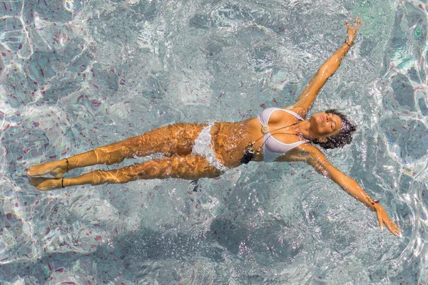 Ung kvinna avkopplande i poolen — Stockfoto