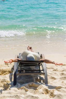  Sevimli kadın rahatlatıcı bir şezlong ve deniz kıyısında bakmak.