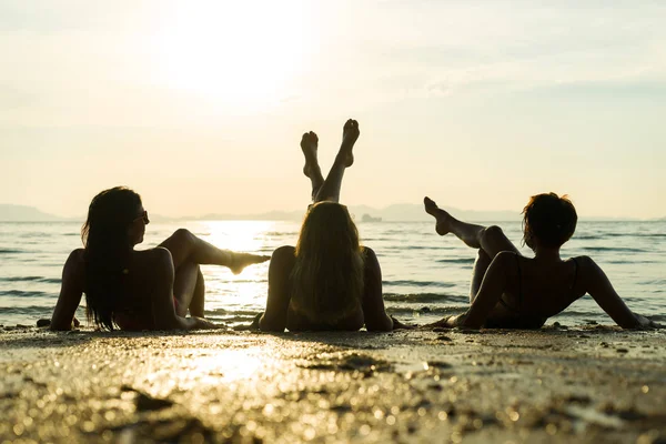 Sylwetka trzy dziewczyny na plaży o zachodzie słońca — Zdjęcie stockowe
