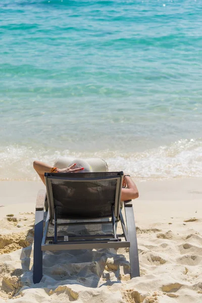 Mulher bonito relaxante em um leito de sol e olhar para a costa do mar . — Fotografia de Stock