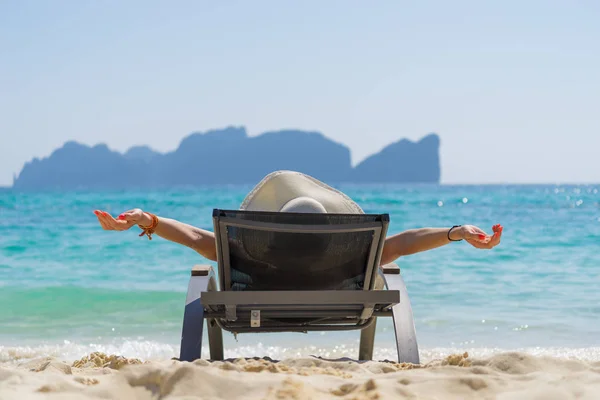 Leuke vrouw ontspannen op een zonnebank en kijk naar de zee kust. — Stockfoto