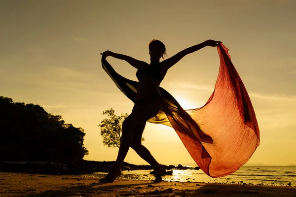 Silueta de una mujer joven y en forma en la playa al atardecer — Foto de Stock