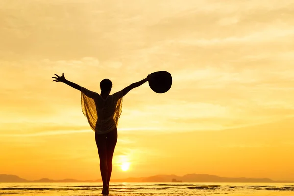 Silueta de una mujer joven y en forma en la playa al atardecer — Foto de Stock