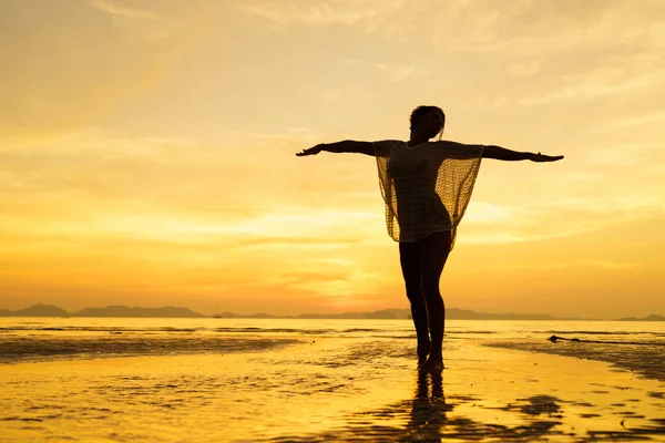 Silueta de una mujer joven y en forma en la playa al atardecer —  Fotos de Stock