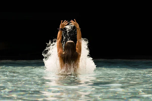 Young beautiful woman making water splash at the pool — Stock Photo, Image