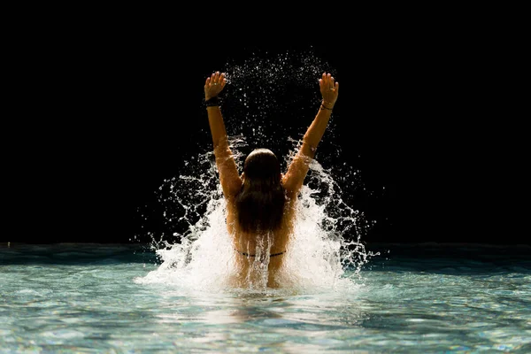 Joven hermosa mujer haciendo salpicaduras de agua en la piscina —  Fotos de Stock