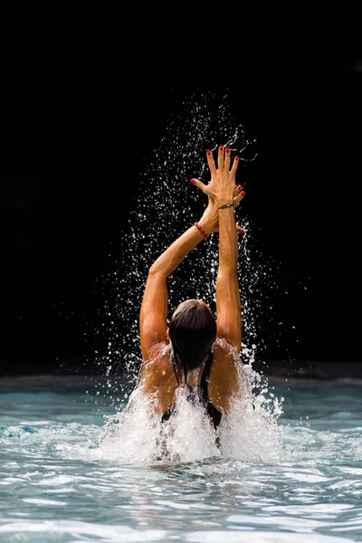 Giovane bella donna che fa schizzi d'acqua in piscina — Foto Stock