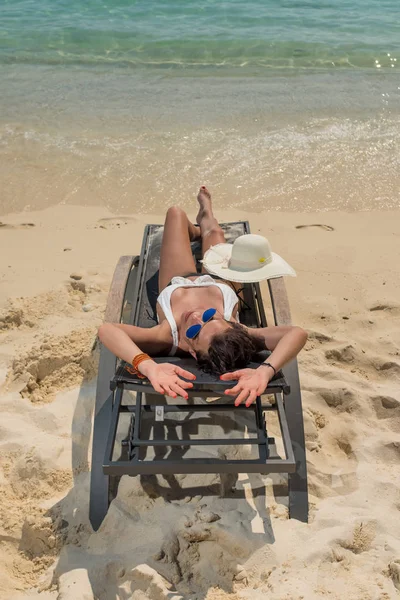 Leuke vrouw ontspannen op een zonnebank en kijk naar de zee kust. — Stockfoto