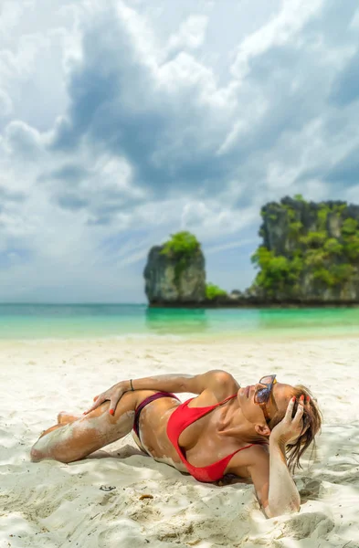 Young woman in bikini laying by the tropical sea