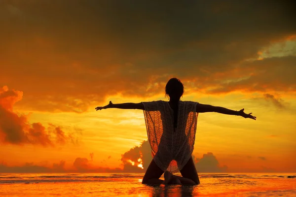 Silhouet van een jonge en fitte vrouw op het strand bij zonsondergang — Stockfoto