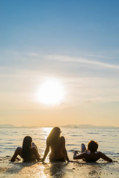 Silhouette di tre ragazze sulla spiaggia al tramonto — Foto Stock